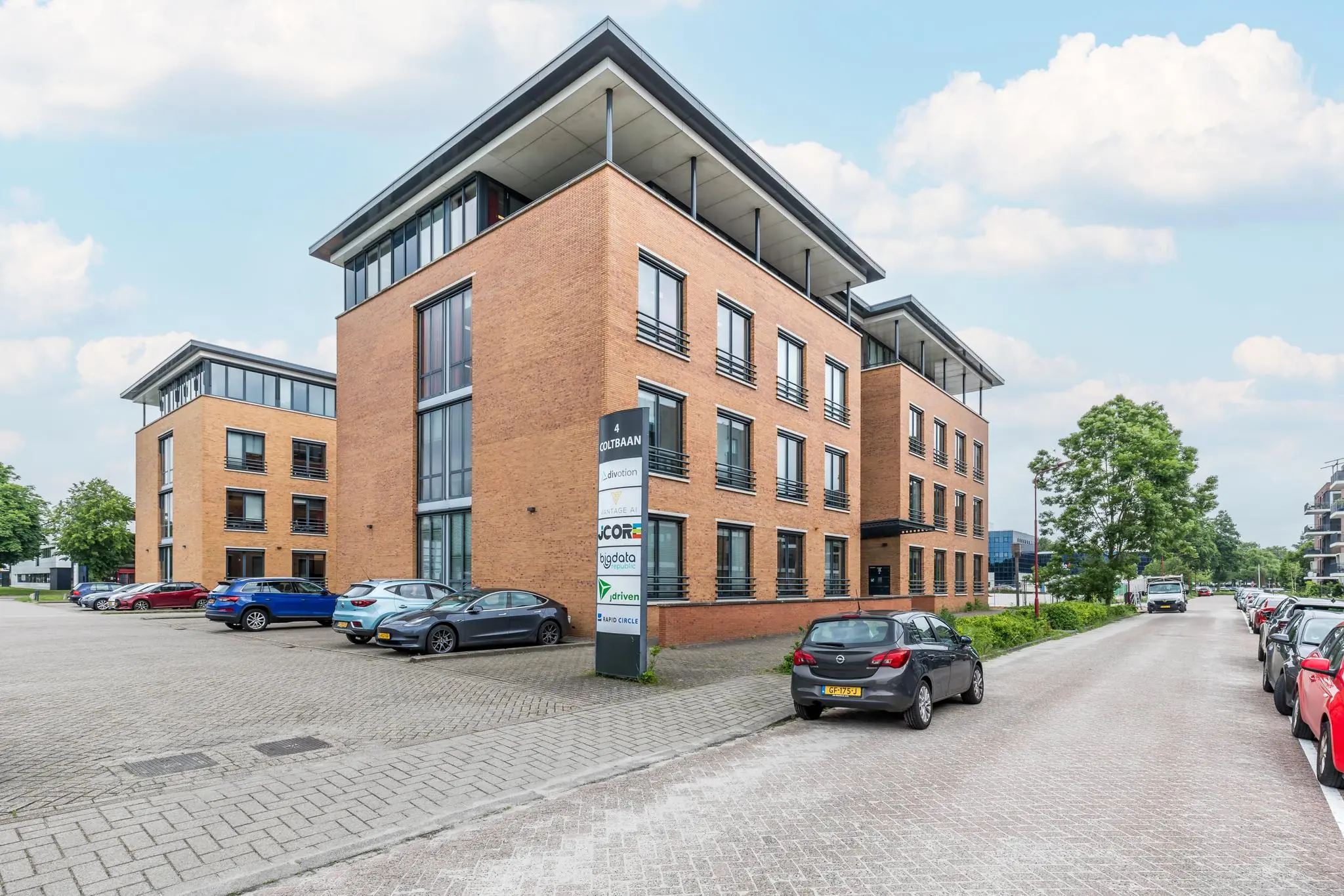 Kantoorgebouw aan de Coltbaan 4 in Nieuwegein met meerdere geparkeerde auto's op een zonnige dag.