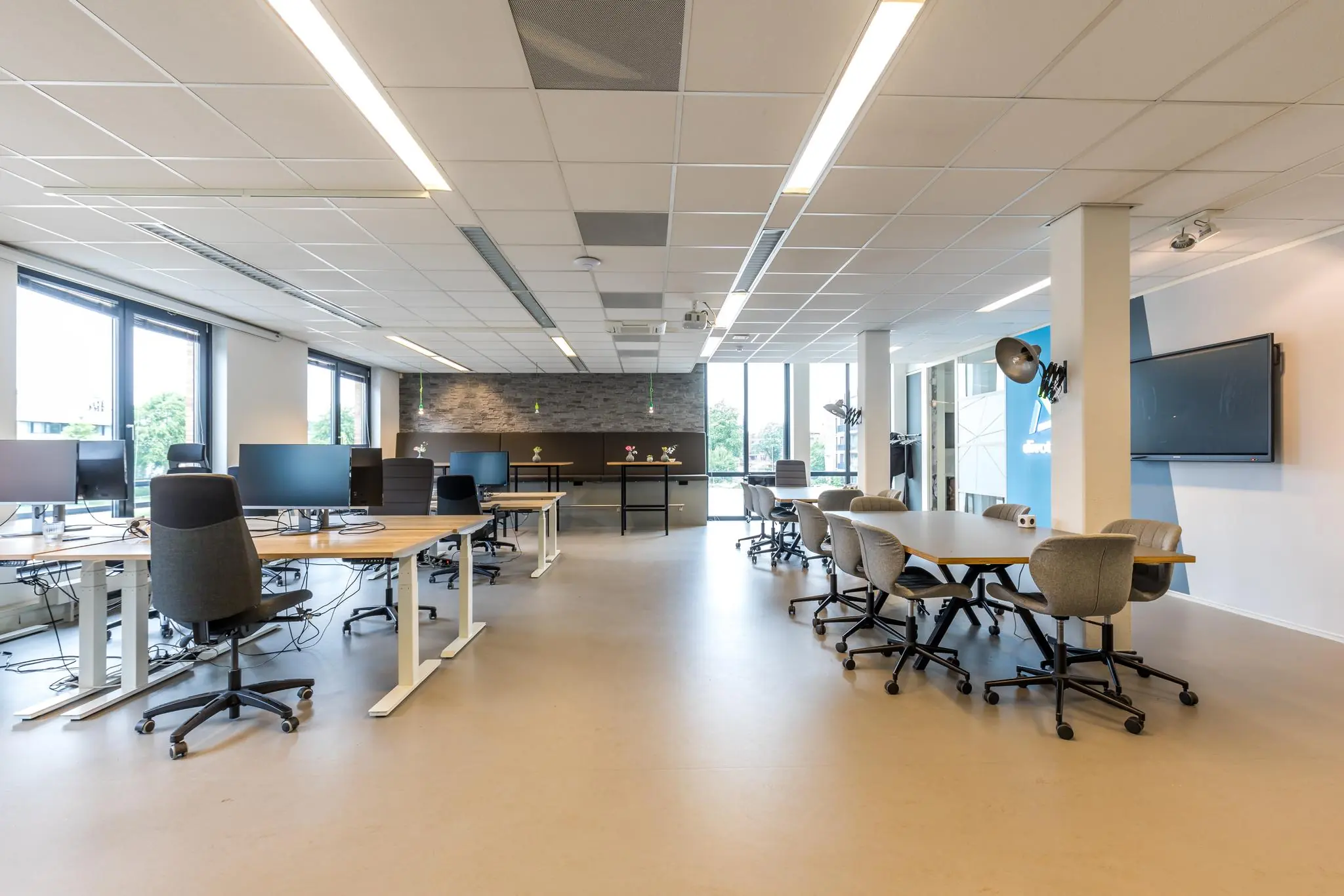 Moderne open kantoorruimte aan de Coltbaan met flexwerkplekken, vergadertafels en grote ramen voor natuurlijk licht.