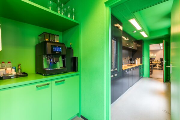 Gekleurde kantoorpantry met espressomachine en zicht op kantine en werkruimte bij Data Republic aan de Coltbaan.