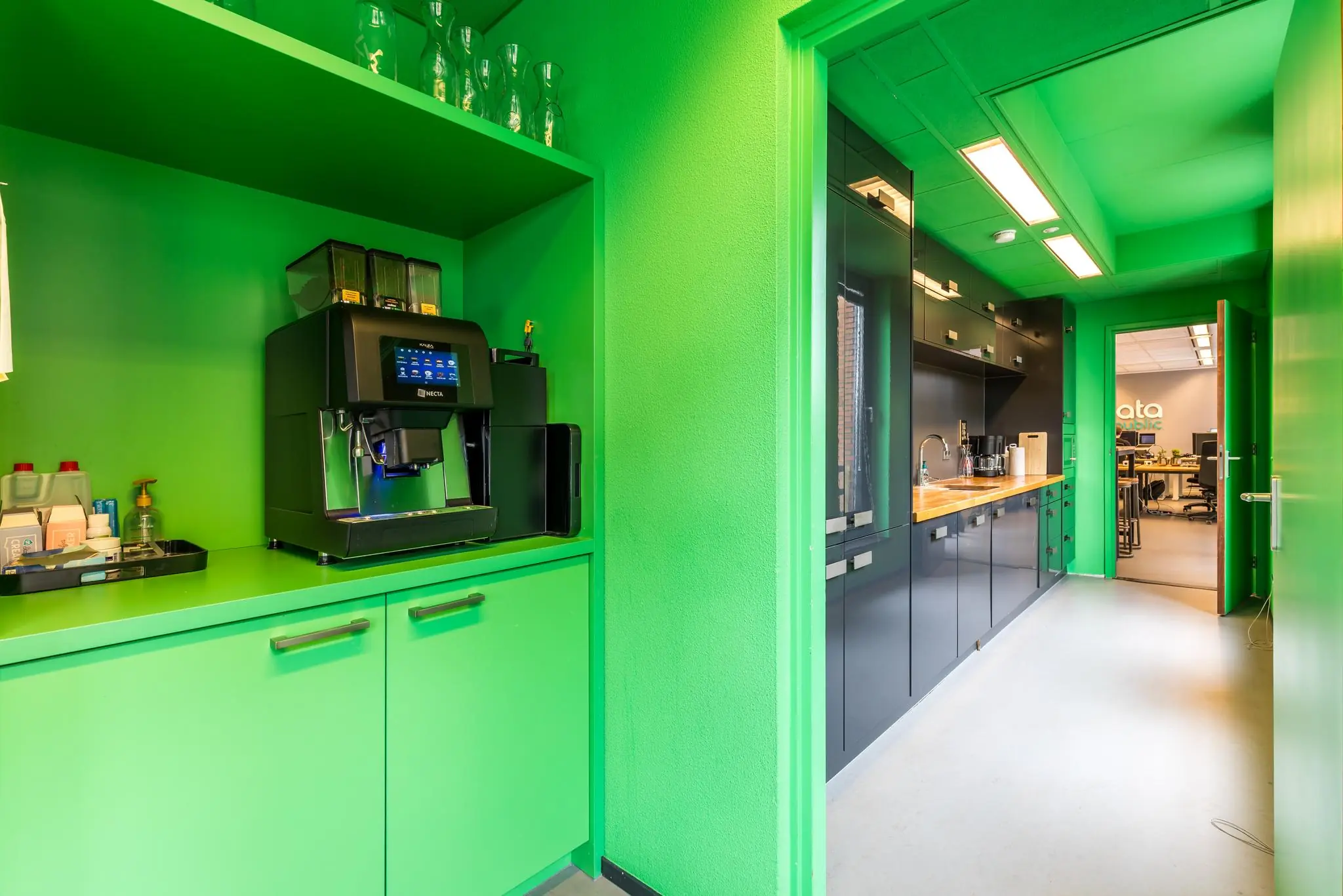 Gekleurde kantoorpantry met espressomachine en zicht op kantine en werkruimte bij Data Republic aan de Coltbaan.