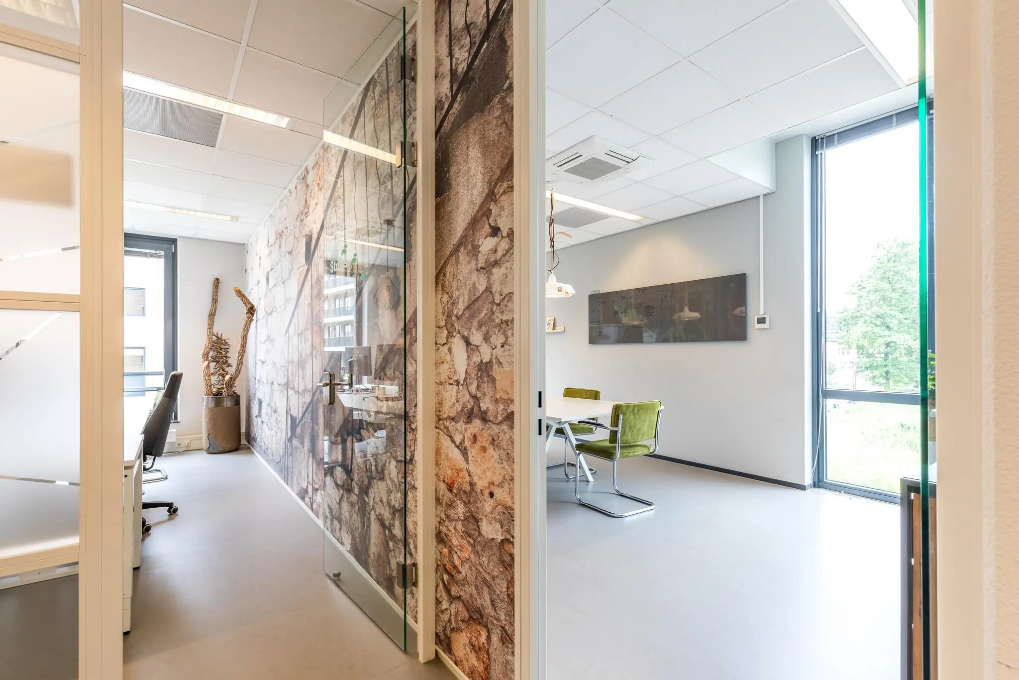 Moderne kantoorruimte aan de Coltbaan met glazen deuren, muurschildering van natuursteen en grote ramen met veel daglicht.