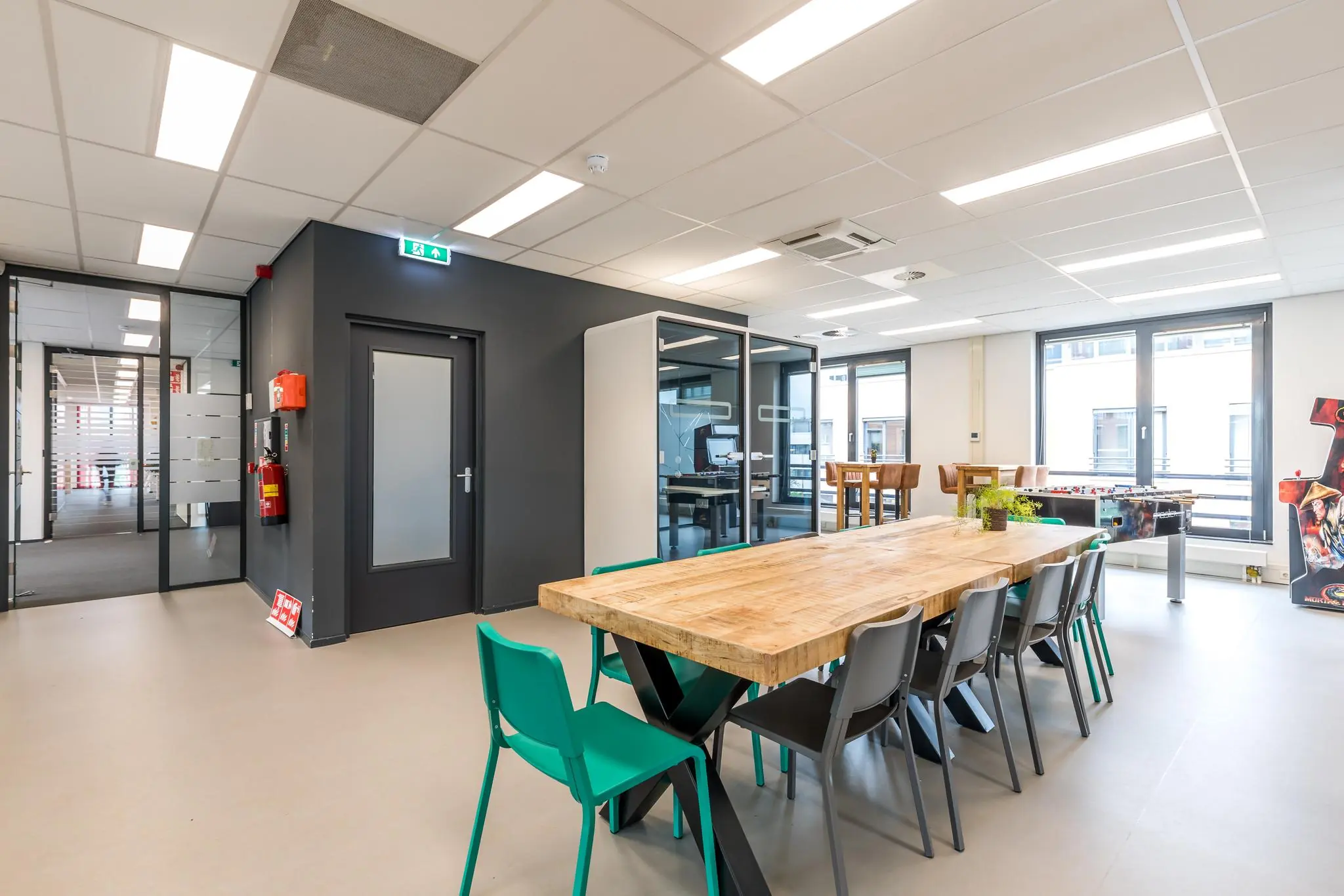 Moderne kantoorruimte op de Coltbaan met een grote houten vergadertafel, belcabines en spelvoorzieningen.