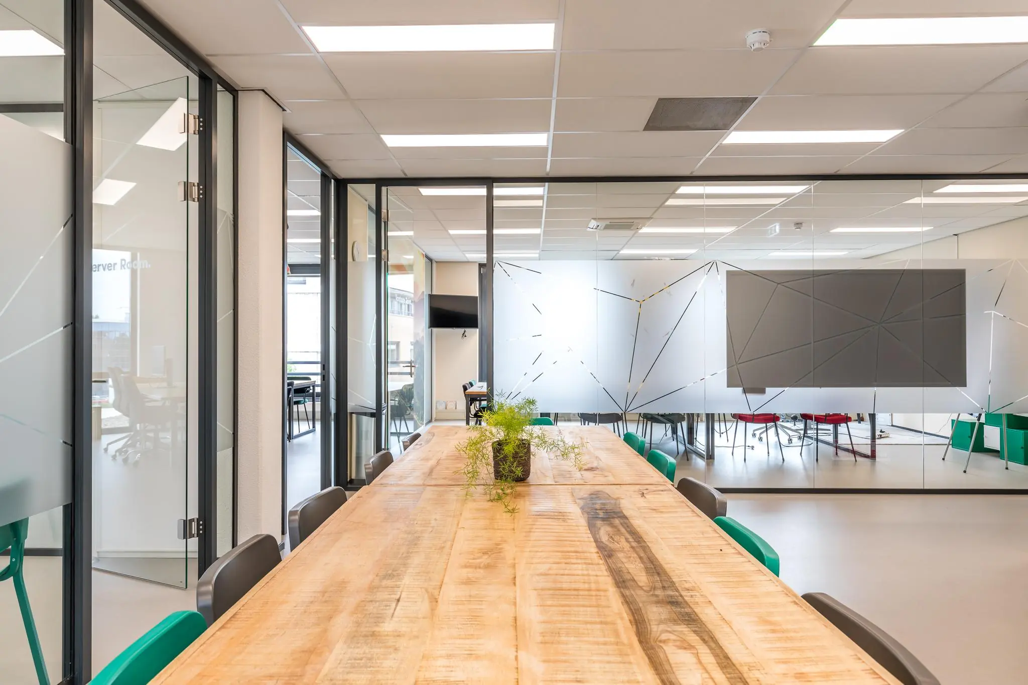 Moderne vergaderruimte met houten tafel, groene stoelen en glazen wanden in een kantoorpand aan de Coltbaan.