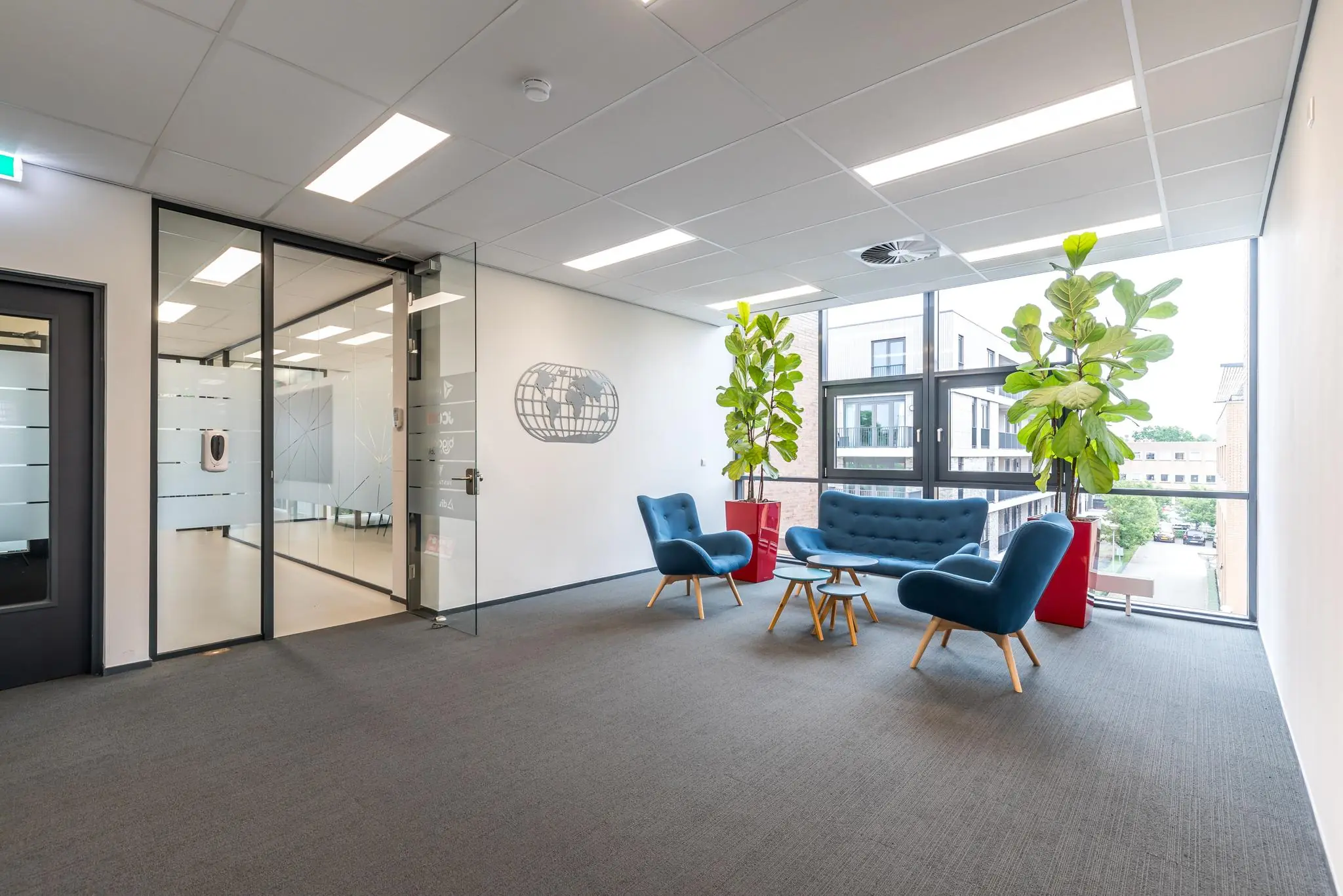 Moderne wachtruimte met blauwe zitmeubelen, grote kamerplanten en veel natuurlijk licht bij kantoor aan de Coltbaan.