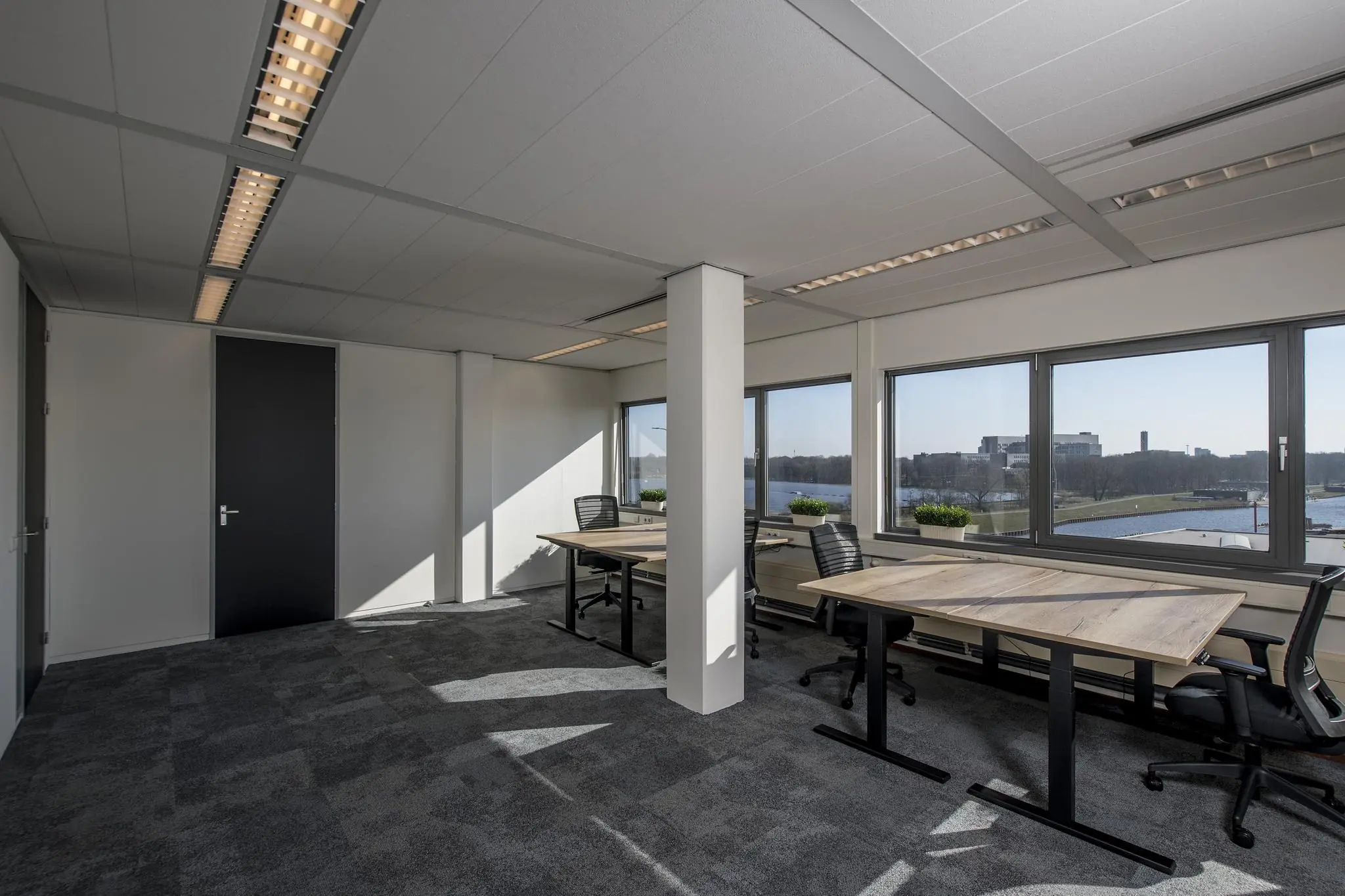 Modern, licht kantoor aan de Vanadiumweg met werkplekken en uitzicht op water en groen.