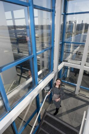 Vrouw met laptop loopt trap op in modern glazen kantoorgebouw aan de Vanadiumweg.