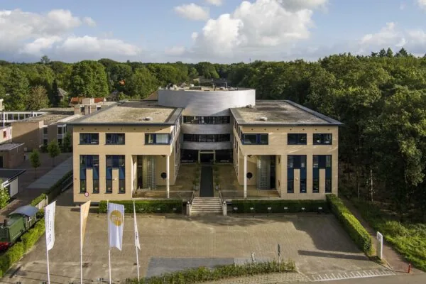 Modern kantoorgebouw aan de Amersfoortseweg, omringd door groen en voorzien van vlaggen en parkeerplaats.