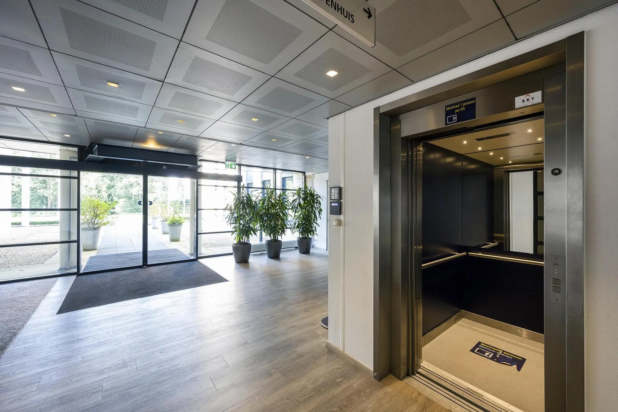 Ingang van een modern kantoorgebouw aan de Amersfoortseweg met open lift en automatisch glazen schuifportaal.