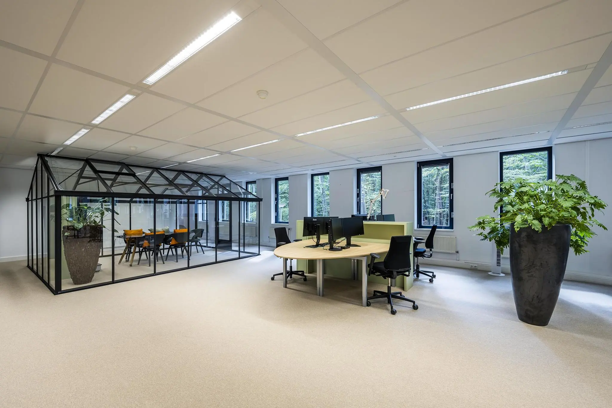 Modern kantoorinterieur aan de Amersfoortseweg met glazen vergaderruimte in kasvorm en open werkplekken.