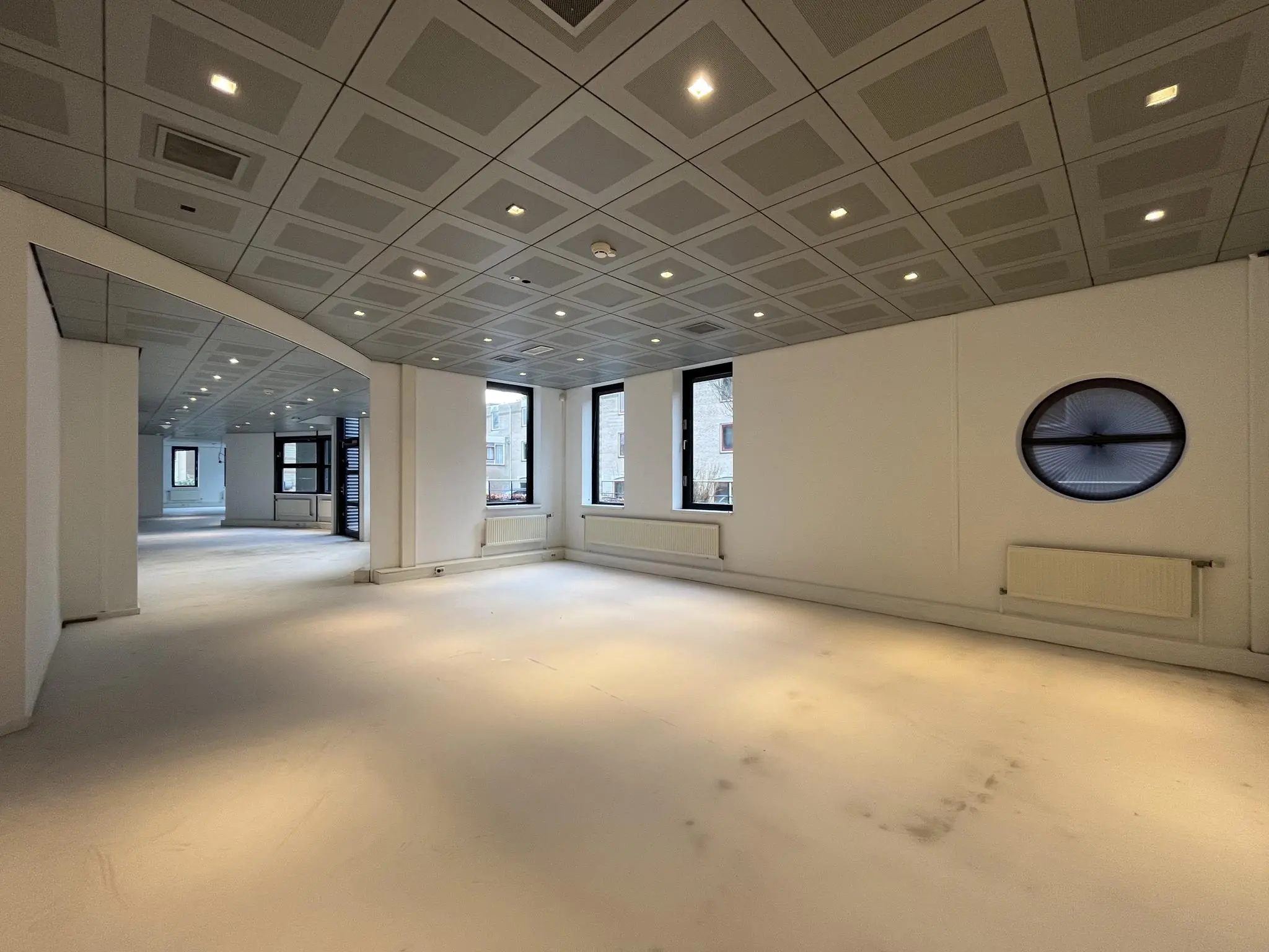 Leeg kantoorpand aan de Amersfoortseweg met systeemplafond, grote ramen en witte muren.