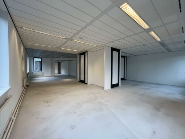 Leegstaand kantoorpand aan de Amersfoortseweg met witte muren, systeemplafond en meerdere glazen deuren.