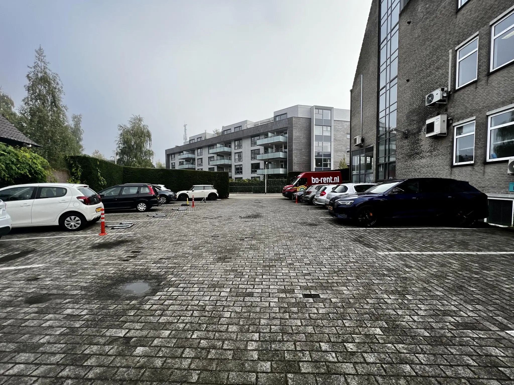 Parkeerterrein aan de Utrechtseweg met geparkeerde auto's en op de achtergrond een modern appartementencomplex.