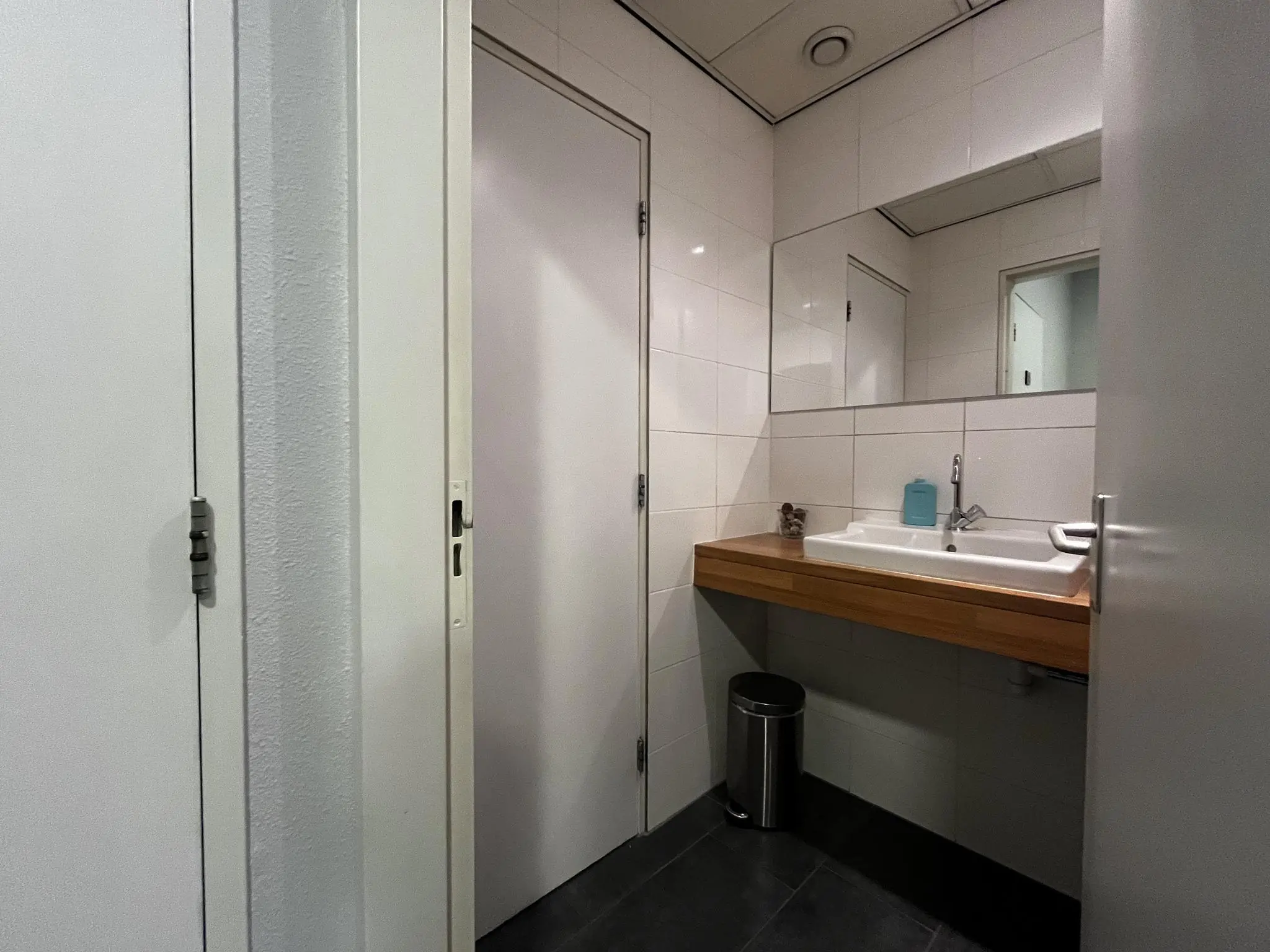 Moderne sanitaire ruimte aan de Utrechtseweg met wastafel, grote spiegel en prullenbak.