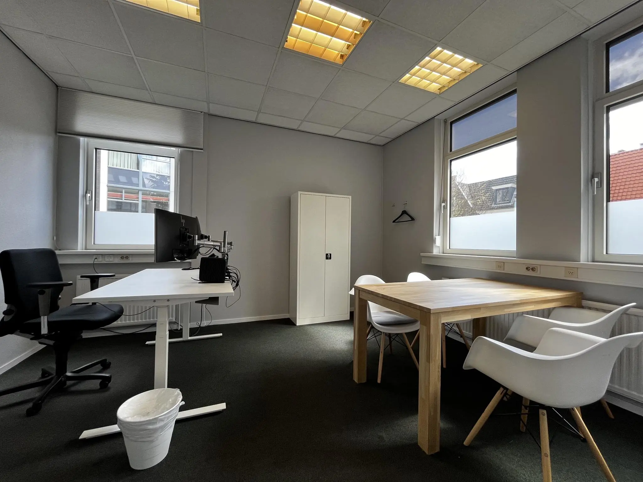 Moderne en licht ingerichte kantoorruimte aan de Utrechtseweg met bureau, vergadertafel en witte stoelen.