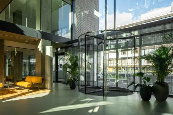 Moderne entreehal van een kantoorgebouw aan de Catharijnesingel met glazen draaideur, gele zitbanken en veel daglicht.