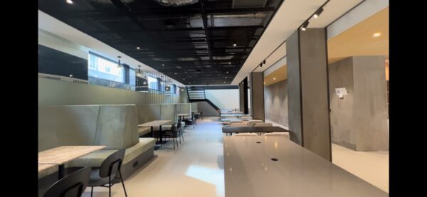 Moderne, minimalistisch ingerichte ruimte aan de Catharijnesingel met zitbanken, tafels en een zwarte trap.