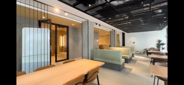 Moderne zithoek en werkruimte aan de Catharijnesingel met houten tafels, mintgroene banken en een industriële plafondafwerking.
