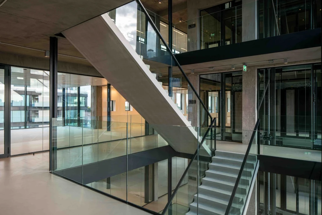 Moderne betonnen trap met glazen balustrades in een open en licht atrium van een kantoorgebouw aan de Catharijnesingel.