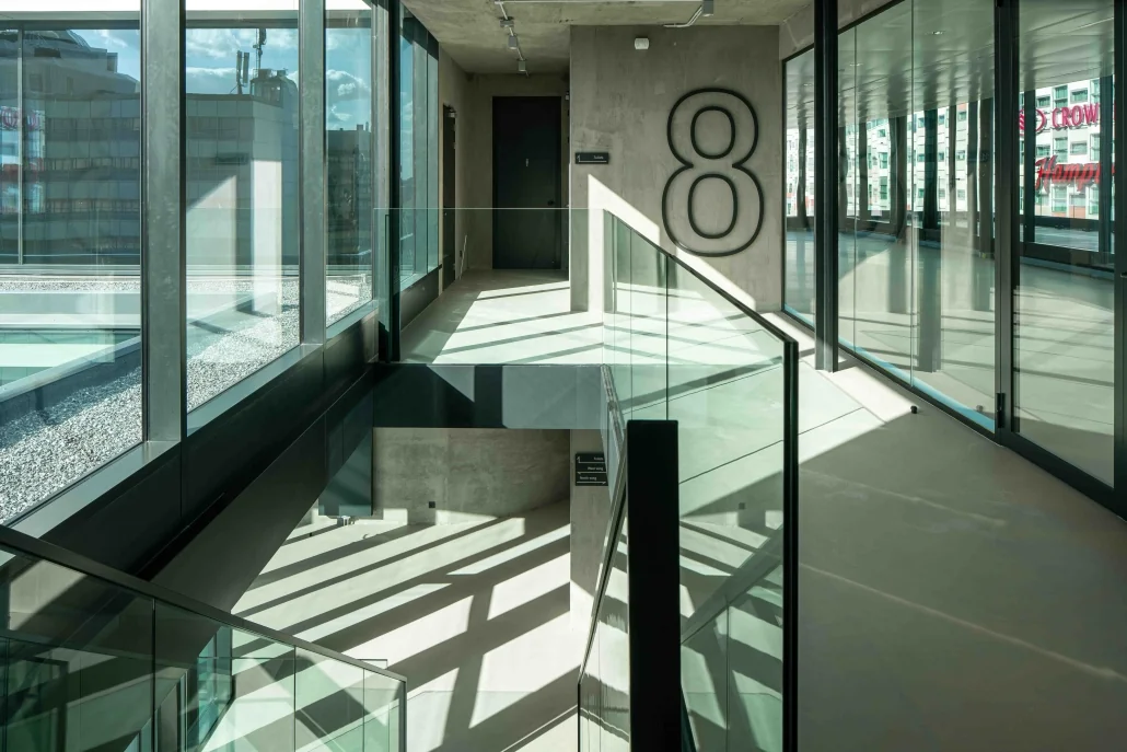 Moderne gang met glazen balustrades en een groot cijfer 8 op de betonnen muur in gebouw aan de Catharijnesingel.