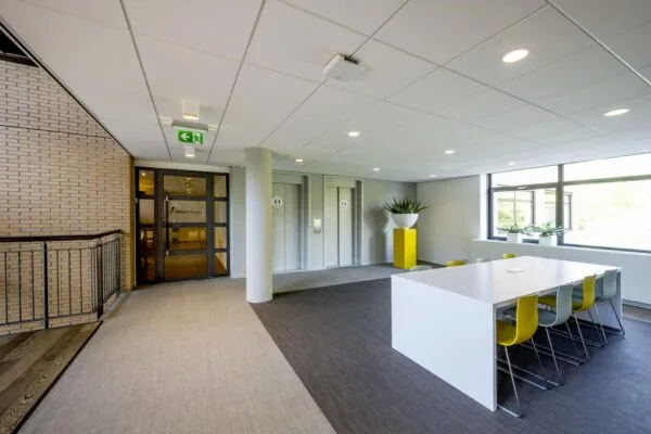 Moderne kantoorruimte aan de Amstelveenseweg met een vergadertafel, liften en planten.