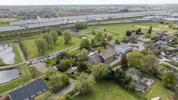 Luchtfoto van de Charloisse Lagedijk in Rotterdam met woonhuizen, groen en snelweg A15 op de achtergrond.