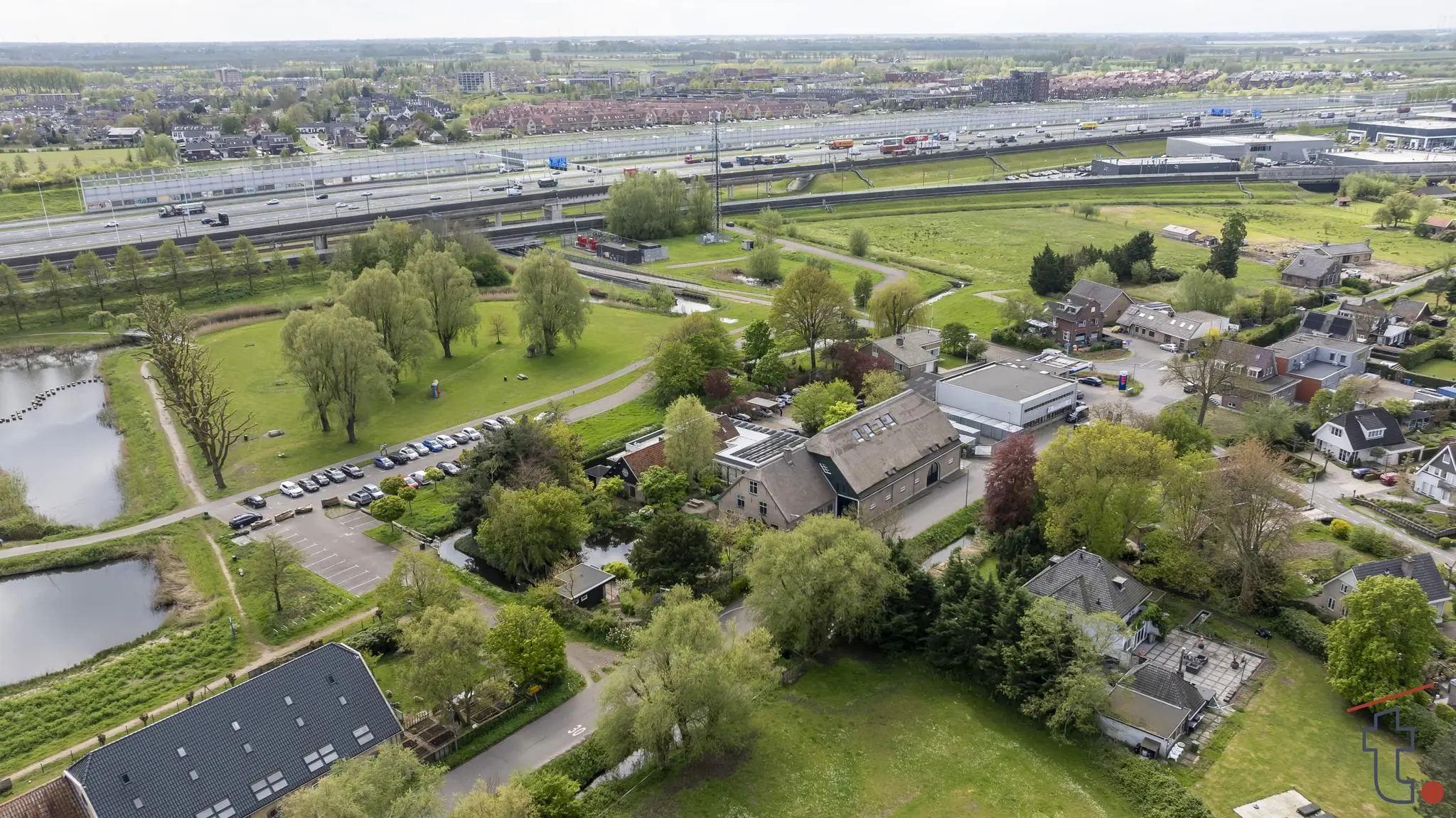Luchtfoto van de Charloisse Lagedijk in Rotterdam met woonhuizen, groen en snelweg A15 op de achtergrond.