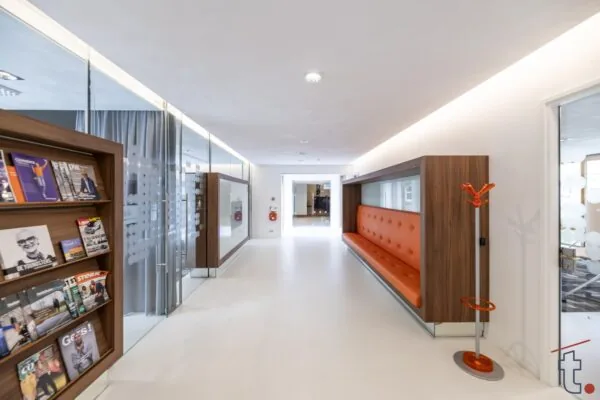 Moderne en lichte gang in een kantoor of wachtruimte aan de Charloisse Lagedijk, met een oranje zithoek, glazen wanden en tijdschriftenrek.