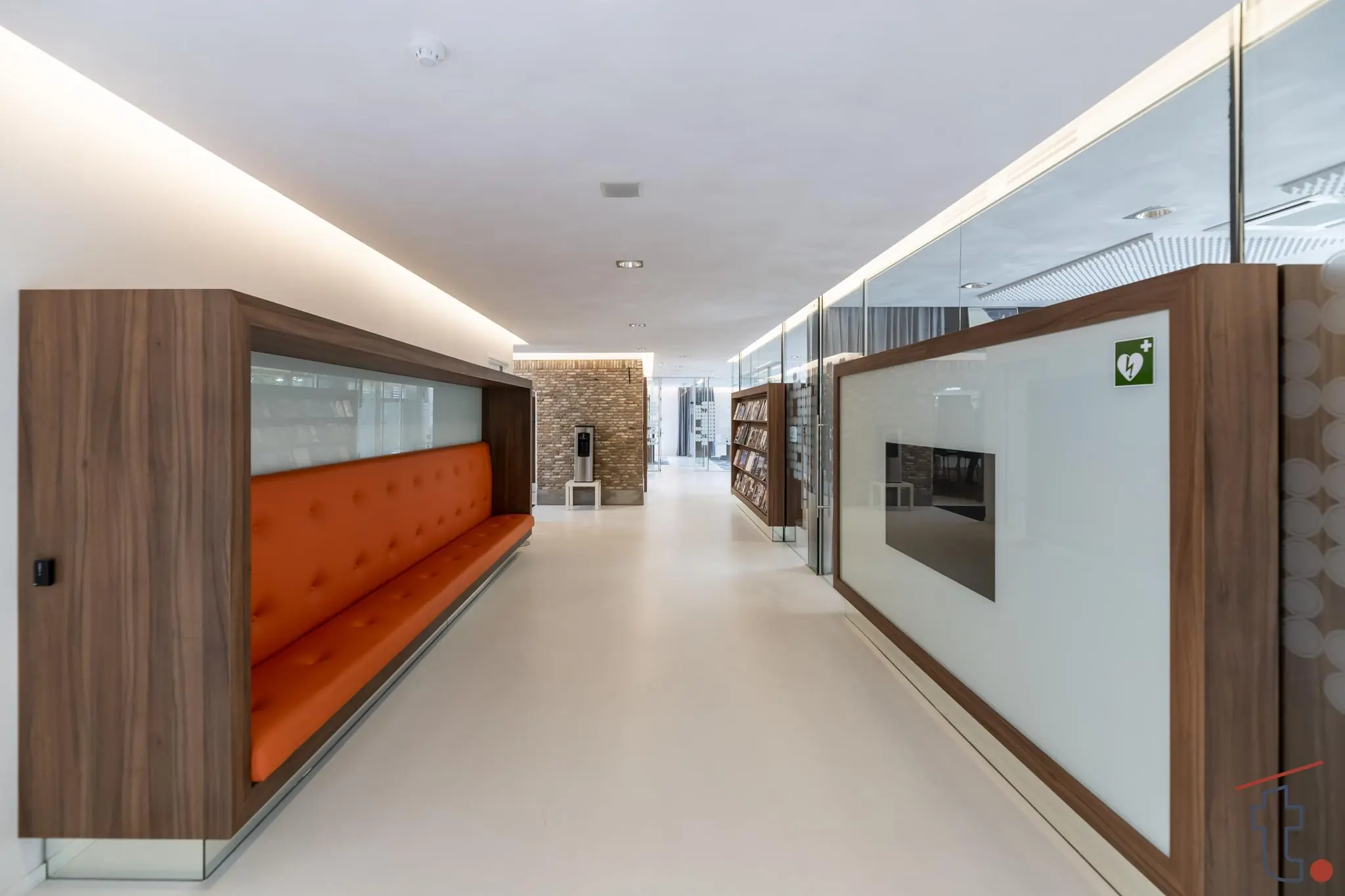 Moderne gang in een gebouw aan de Charloisse Lagedijk met houten accenten, een oranje zitbank en glazen wanden.