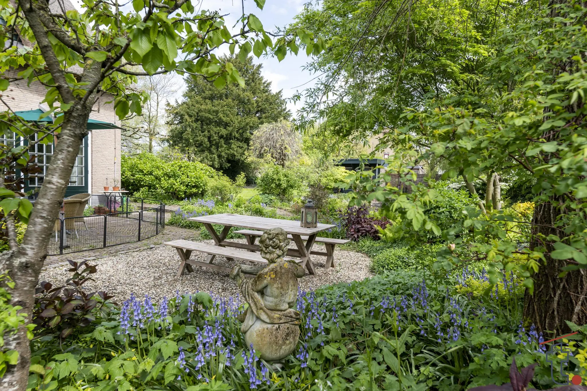 Buitenruimte met picknicktafels, beeldhouwwerk en bloeiende tuin aan de Charloisse Lagedijk.