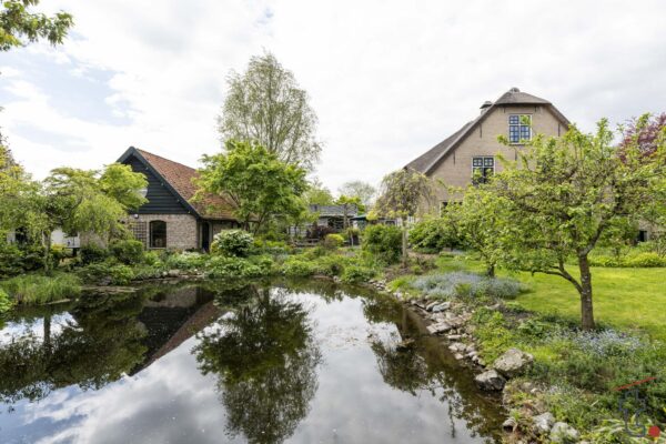 Boerderij aan de Charloisse Lagedijk met weelderige tuin en vijver op de voorgrond.