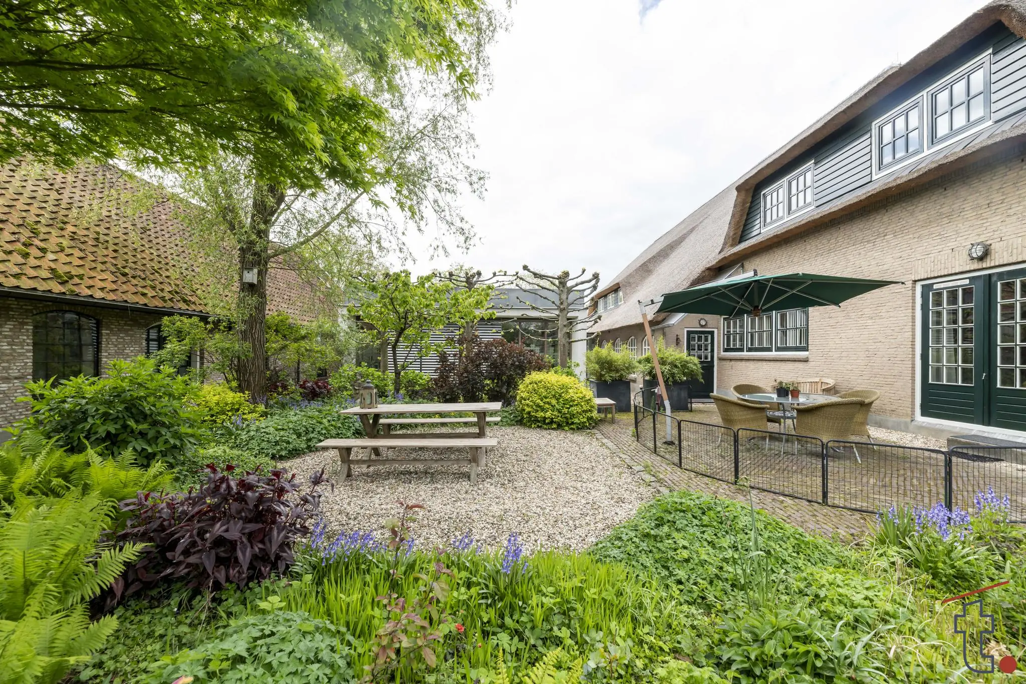 Groene binnentuin met picknicktafels en terras bij een gerestaureerde boerderij aan de Charloisse Lagedijk.