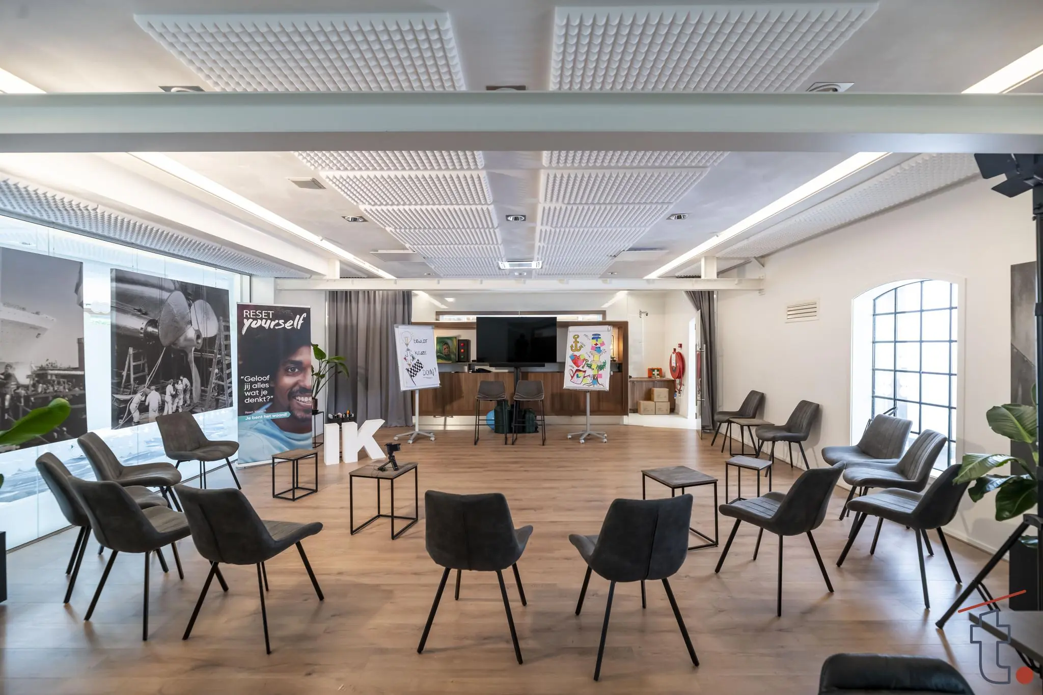 Moderne vergaderruimte aan de Charloisse Lagedijk met in een kring opgestelde stoelen, posters, een scherm en inspirerende banners.