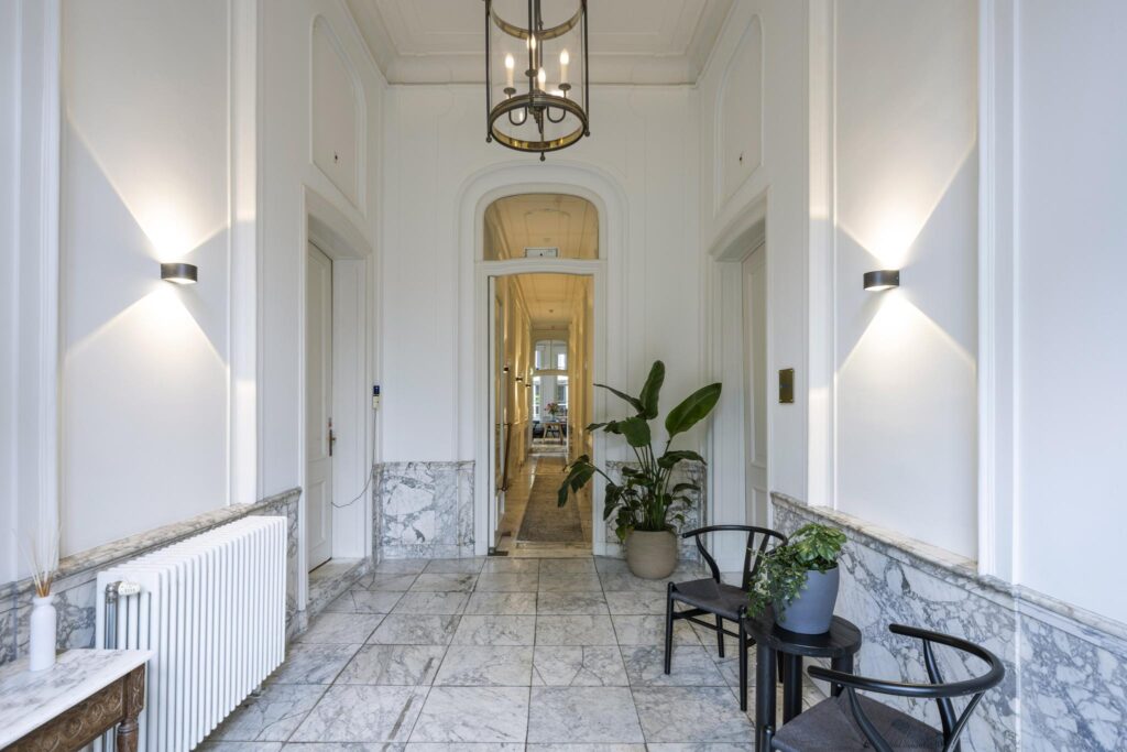 Luxe marmeren entreehal aan de Herengracht met klassieke details, moderne verlichting en stijlvolle planten.