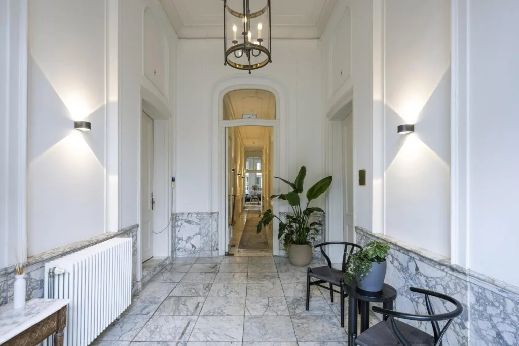 Luxe marmeren entreehal aan de Herengracht met klassieke details, moderne verlichting en stijlvolle planten.