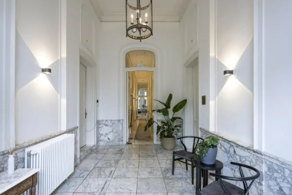 Luxe marmeren entreehal aan de Herengracht met klassieke details, moderne verlichting en stijlvolle planten.