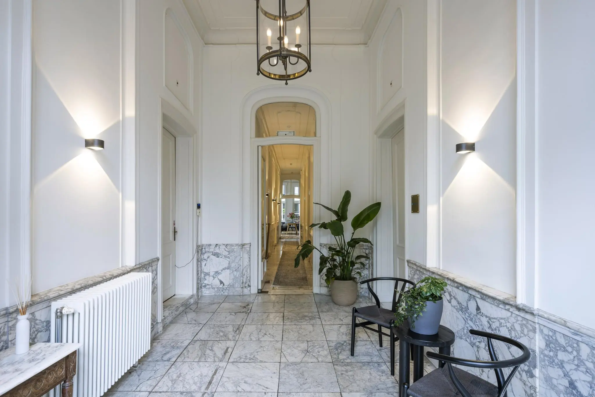 Luxe marmeren entreehal aan de Herengracht met klassieke details, moderne verlichting en stijlvolle planten.