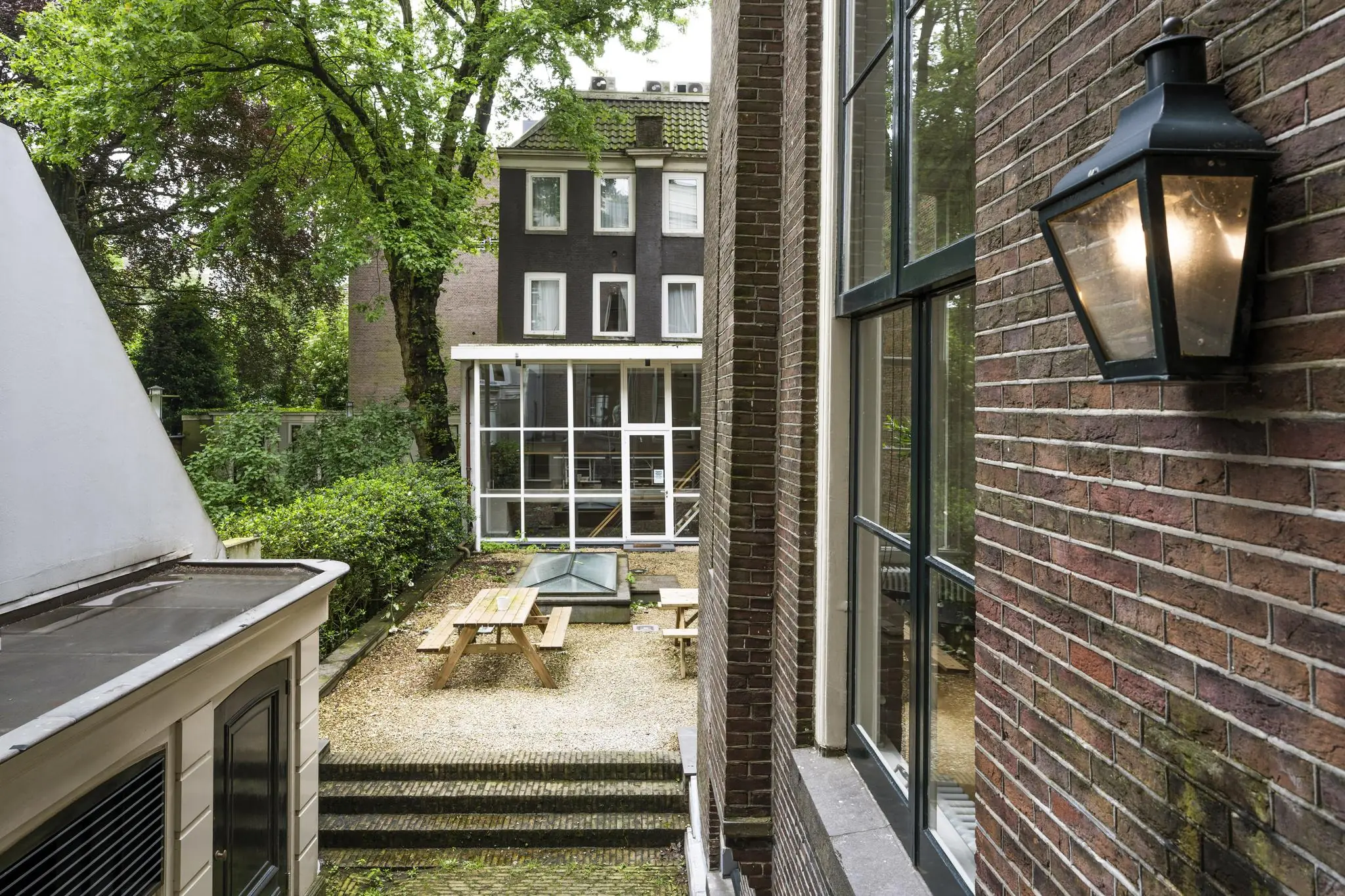 Binnenplaats met houten picknicktafels en omliggende gevels aan de Herengracht in Amsterdam.