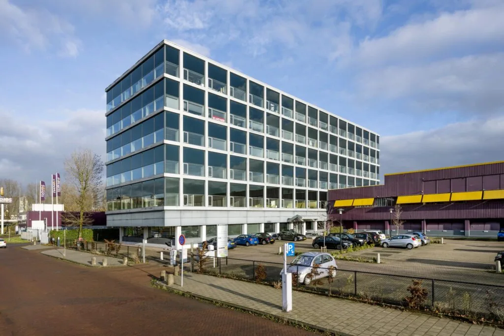 Kantoorgebouw aan de Spaklerweg met parkeerplaats op de voorgrond en een naastgelegen paars-geel pand.
