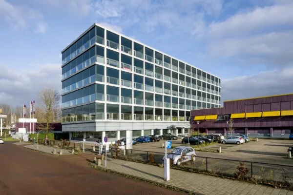 Kantoorgebouw aan de Spaklerweg met parkeerplaats op de voorgrond en een naastgelegen paars-geel pand.