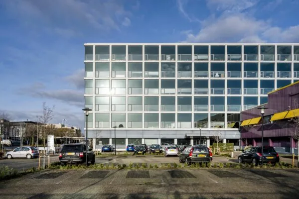 Modern kantoorgebouw aan de Spaklerweg met parkeerplaats en geparkeerde auto's op de voorgrond.