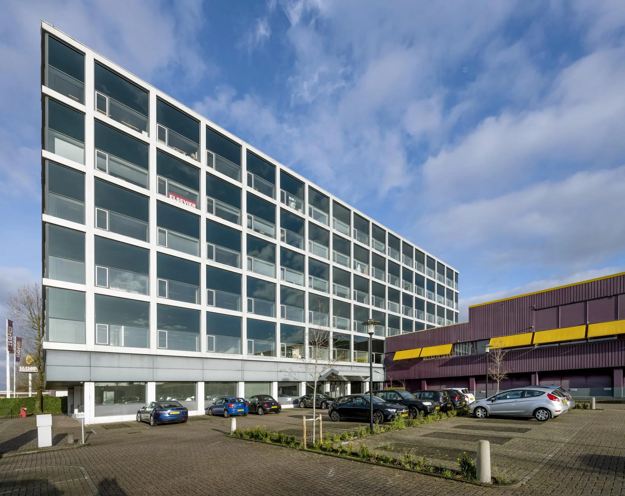 Modern kantoorgebouw aan de Spaklerweg in Amsterdam met parkeerplaatsen op de voorgrond.
