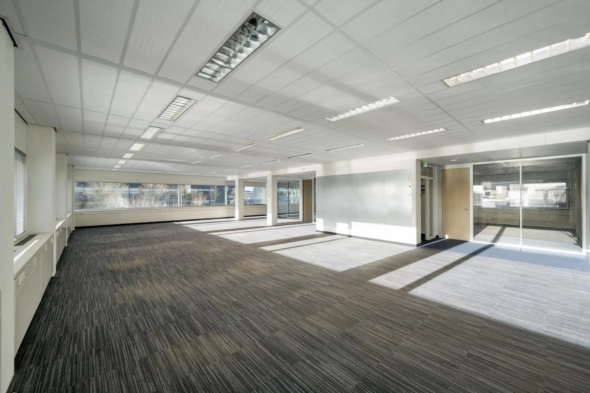 Licht en ruim leeg kantoor aan de Spaklerweg met grote ramen en systeemplafond.