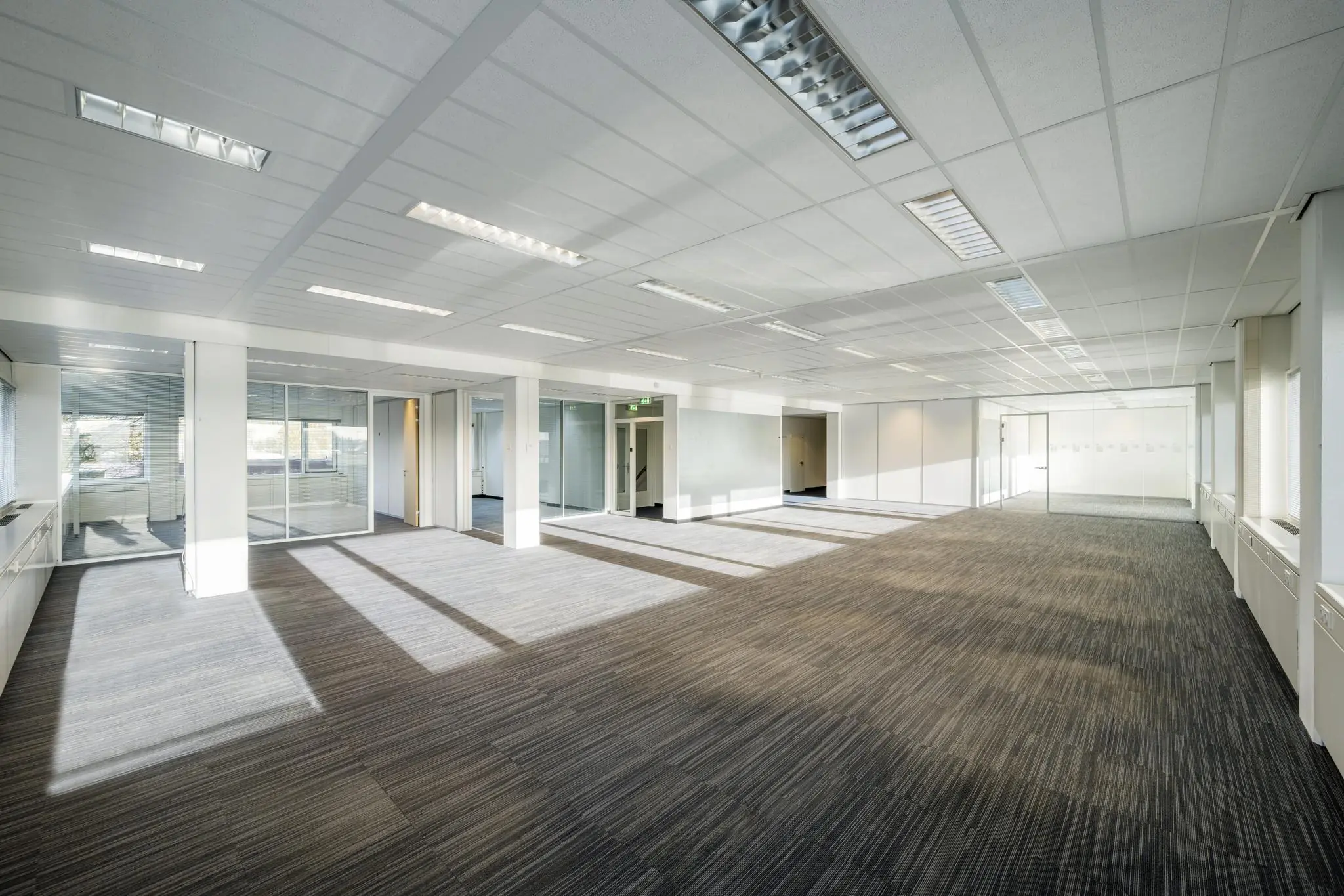 Licht en ruim leeg kantoorpand aan de Spaklerweg met grote ramen en glazen binnenwanden.