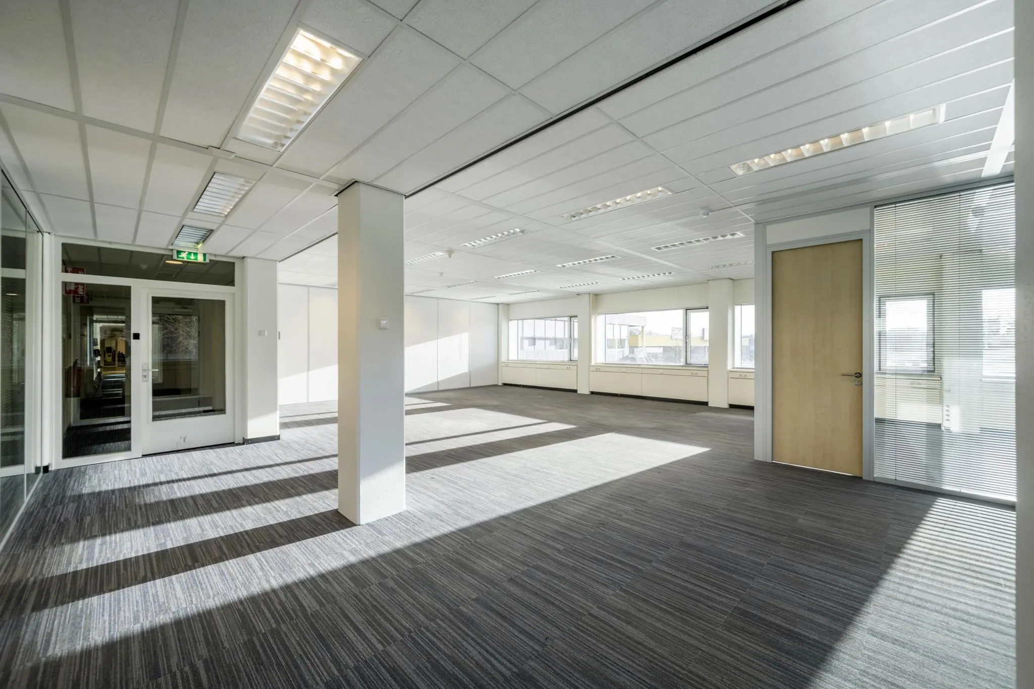 Licht en modern leeg kantoorpand aan de Spaklerweg met grote ramen en glazen binnenwanden.