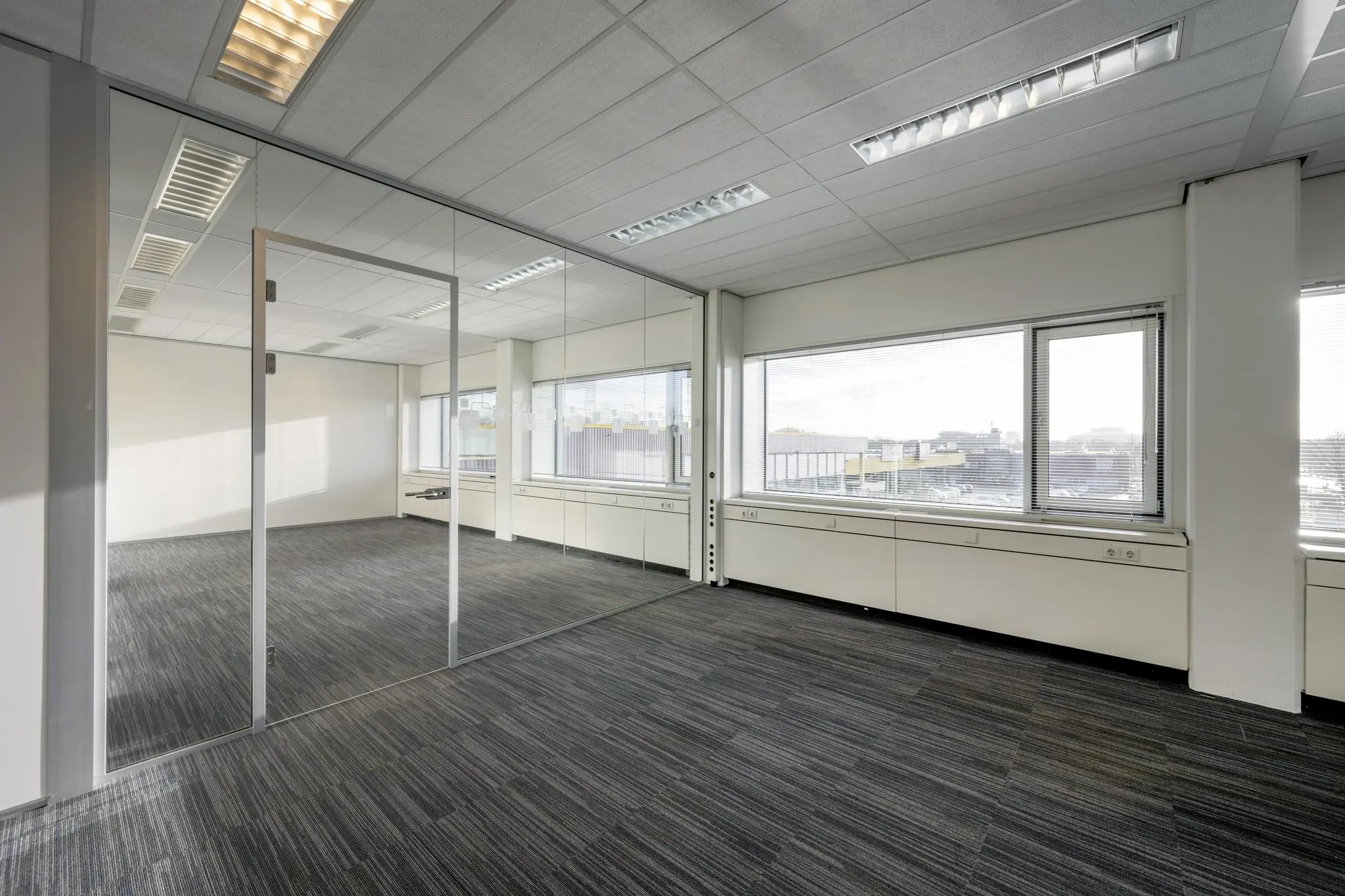 Licht en ruim kantoor aan de Spaklerweg met glazen tussenwand en grote ramen met uitzicht op het bedrijventerrein.