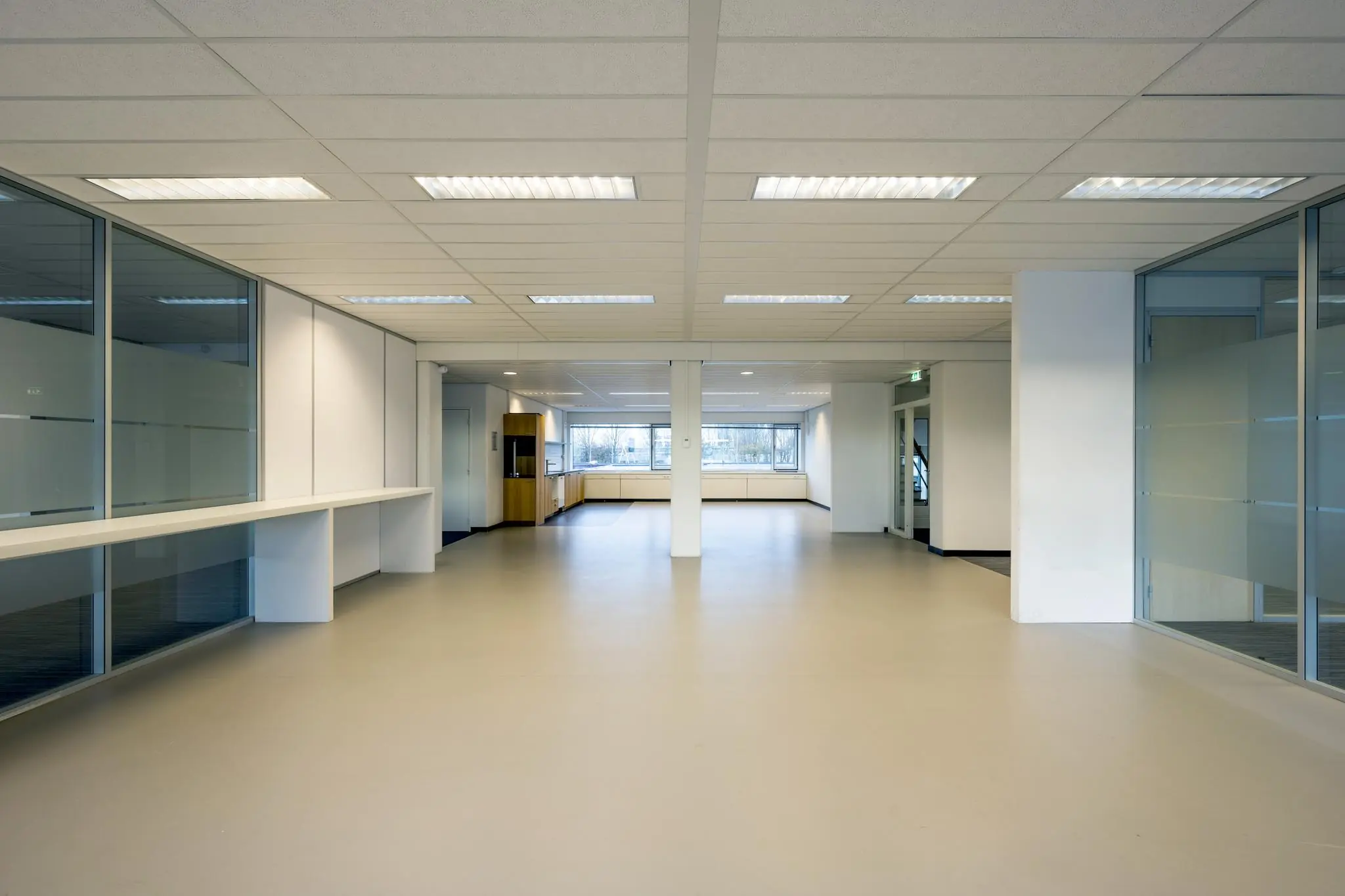 Lichte, lege kantoorruimte aan de Spaklerweg met grote ramen en glazen scheidingswanden.