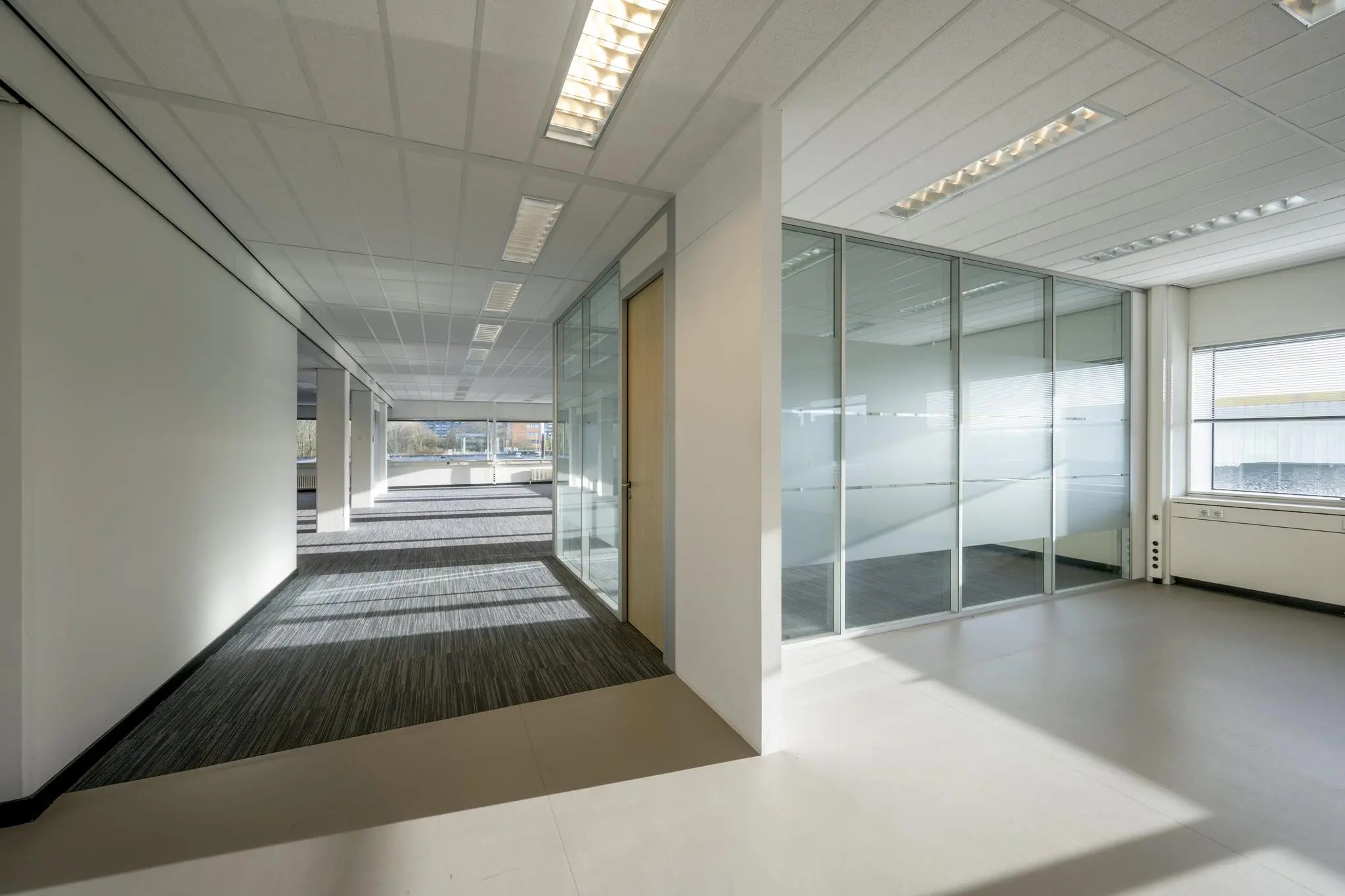 Lichte, moderne kantoorruimte aan de Spaklerweg met glazen wanden en grote ramen.