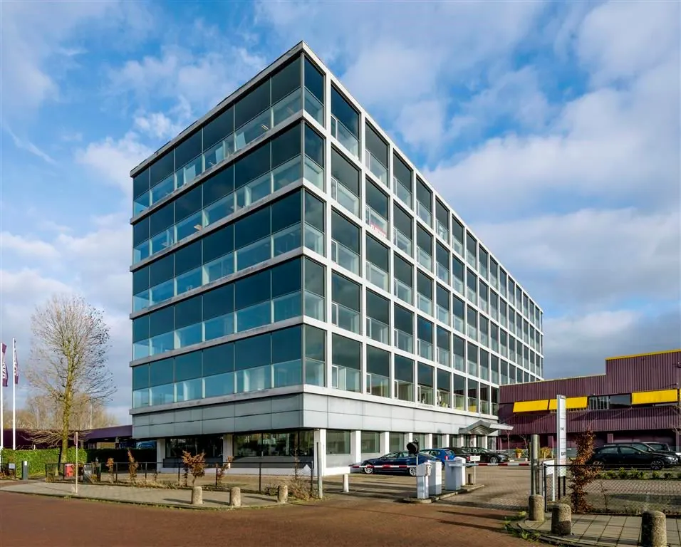 Modern kantoorgebouw aan de Spaklerweg met glazen gevel en aangrenzend parkeerterrein.