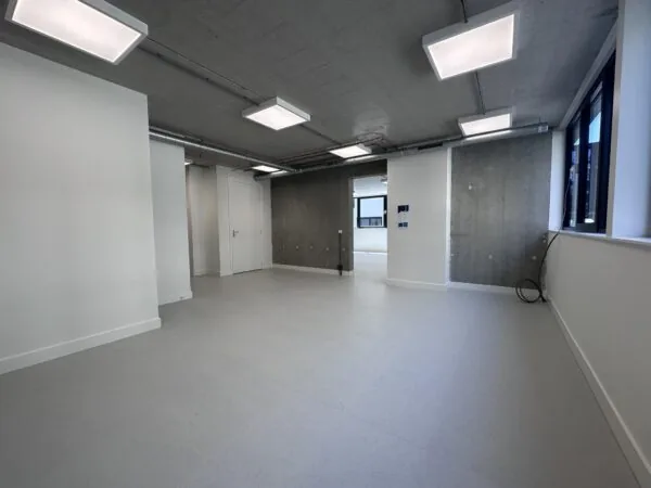 Lege, moderne kantoorruimte aan de Willem Parelstraat met betonnen muren en plafond, grote ramen en ingebouwde verlichting.