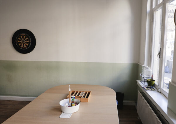 Vergaderruimte aan de Raadhuisstraat met een dartbord aan de muur en een tafel met kantoorbenodigdheden.
